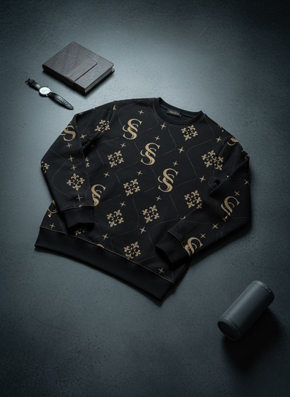 Black sweater with gold patterns on a dark surface